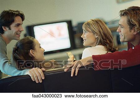 Two couples watching TV together, chatting, rear view View Large Photo Image Stock Image - Two couples watching TV together, chatting, rear view. Fotosearch