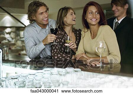 Stock Image - Two young couples together at bar. Fotosearch