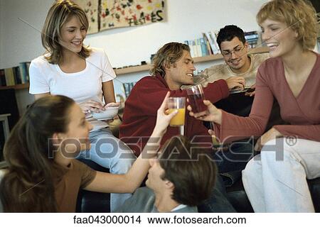 Picture - Two young women clinking glasses at home gathering of friends. Fotosearch