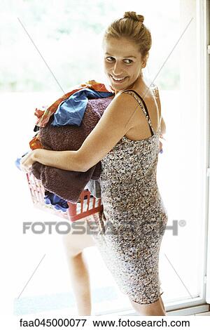 Stock Photo - Woman carrying full laundry basket glancing sideways over shoulder. Fotosearch
