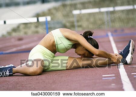 Woman doing stretches on running track, touching forehead to knee View Large Photo Image Stock Photo - Woman doing stretches on running track, touching forehead to knee. Fotosearch
