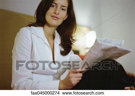 Woman holding newspaper, smiling at camera View Large Photo Image Picture - Woman holding newspaper, smiling at camera. Fotosearch
