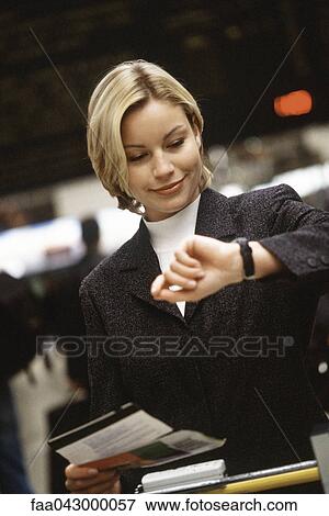 Woman holding travel ticket looking at watch View Large Photo Image Stock Photo - Woman holding travel ticket looking at watch. Fotosearch
