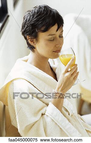 Stock Photography - Woman in bathrobe drinking orange juice. Fotosearch