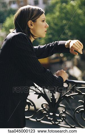 Woman leaning against wrought iron railing looking at watch View Large Photo Image Stock Image - Woman leaning against wrought iron railing looking at watch. Fotosearch