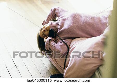 Woman lying on back on bed using phone, smiling, looking away View Large Photo Image Stock Photography - Woman lying on back on bed using phone, smiling, looking away. Fotosearch