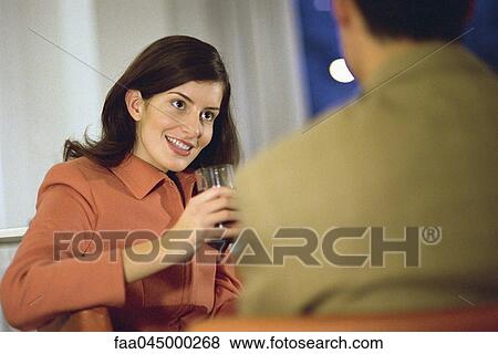 Woman sitting with man, holding glass of red wine View Large Photo Image Stock Photo - Woman sitting with man, holding glass of red wine. Fotosearch