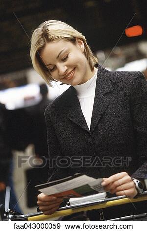 Stock Photo - Woman smiling looking at travel ticket. Fotosearch