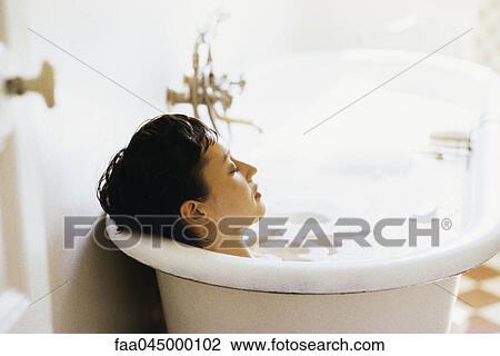 Stock Image - Woman soaking in bubble bath. Fotosearch