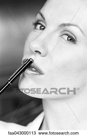 Woman touching lips with pen, glancing sideways at camera View Large Photo Image Stock Image - Woman touching lips with pen, glancing sideways at camera. Fotosearch