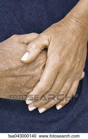 Stock Image - Woman's hand resting on top of man's hand, close-up. Fotosearch