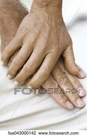 Stock Image - Woman's hand resting on top of man's hand, close-up. Fotosearch