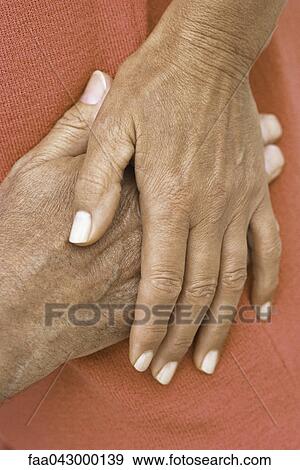 Stock Photo - Woman's hand resting on top of man's hand, close-up. Fotosearch