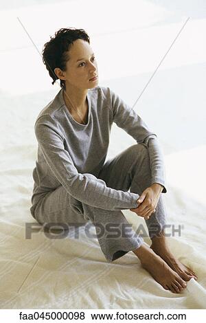 Women in athletic wear sitting on floor hugging knees looking away View Large Photo Image Stock Photo - Women in athletic wear sitting on floor hugging knees looking away. Fotosearch