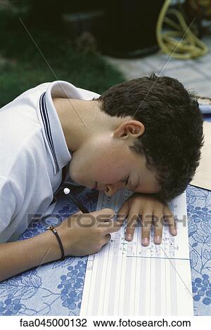 Stock Image - Young boy correcting music homework. Fotosearch