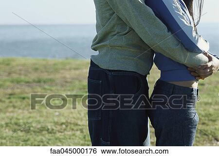 Stock Photograph - Young couple embracing, cropped view. Fotosearch