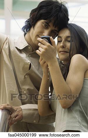 Young couple looking at cell phone together View Large Photo Image Stock Photo - Young couple looking at cell phone together. Fotosearch
