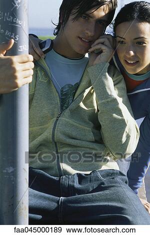 Stock Photo - Young friends listening to cell phone together. Fotosearch