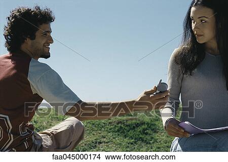 Picture - Young man showing cell phone to woman. Fotosearch