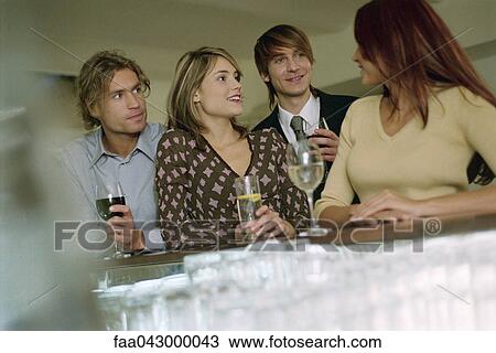 Stock Image - Young woman talking with friends at bar. Fotosearch