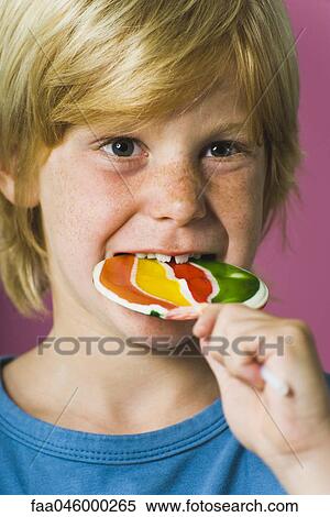 Boy biting into lollipop View Large Photo Image Stock Photography - Boy biting into lollipop. Fotosearch