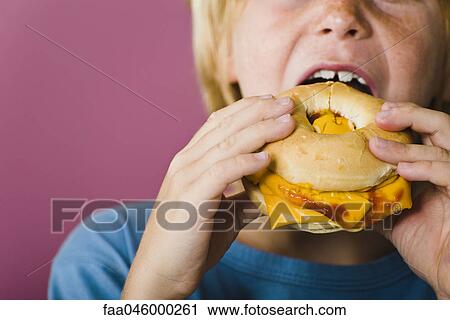 Boy eating bagel and cheese sandwich, cropped View Large Photo Image Stock Image - Boy eating bagel and cheese sandwich, cropped. Fotosearch