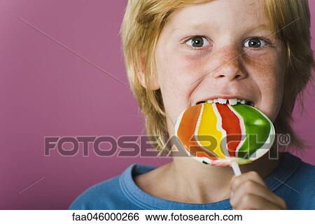 Boy eating lollipop, portrait View Large Photo Image Stock Photograph - Boy eating lollipop, portrait. Fotosearch