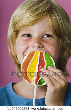 Stock Image - Boy holding large lollipop in front of face. Fotosearch