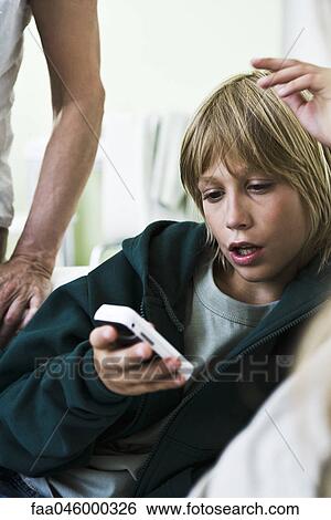 Boy looking at cell phone View Large Photo Image Stock Photograph - Boy looking at cell phone. Fotosearch