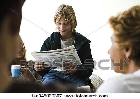 Boy reading newspaper, family members in foreground View Large Photo Image Stock Photo - Boy reading newspaper, family members in foreground. Fotosearch
