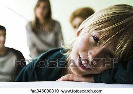 Stock Image - Boy resting head on arms, smiling at camera. Fotosearch