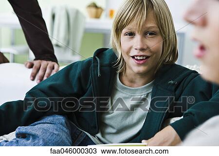 Boy sitting on sofa, talking with family members View Large Photo Image Stock Image - Boy sitting on sofa, talking with family members. Fotosearch