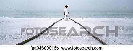Boy standing at end of footpath on beach, looking at sea View Large Photo Image Stock Photography - Boy standing at end of footpath on beach, looking at sea. Fotosearch