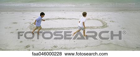 Boys running on beach, chasing each other around circle drawn in sand View Large Photo Image Stock Photo - Boys running on beach, chasing each other around circle drawn in sand. Fotosearch