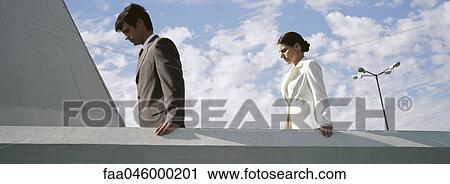 Businessman and businesswoman on rooftop, both looking down contemplatively View Large Photo Image Stock Image - Businessman and businesswoman on rooftop, both looking down contemplatively. Fotosearch