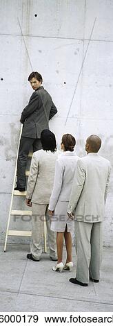 Stock Photo - Businessman climbing ladder, looking over shoulder at professionals lined up behind him. Fotosearch
