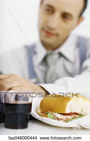 Picture - Businessman focusing on work, lunch in foreground. Fotosearch