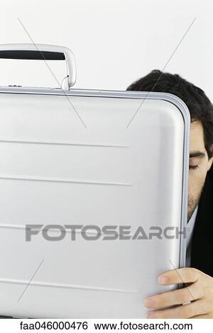 Stock Photograph - Businessman hiding behind briefcase. Fotosearch