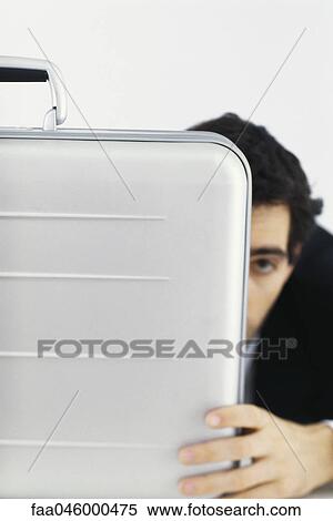 Stock Photography - Businessman hiding behind briefcase. Fotosearch
