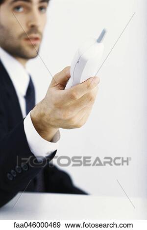 Businessman holding out cordless phone View Large Photo Image Stock Photo - Businessman holding out cordless phone. Fotosearch