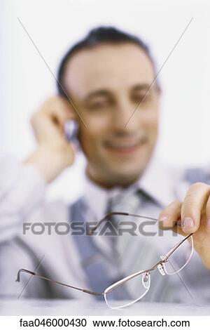 Businessman on phone call, holding glasses in hand View Large Photo Image Stock Image - Businessman on phone call, holding glasses in hand. Fotosearch