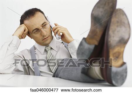 Businessman on phone call with feet up on desk View Large Photo Image Stock Photo - Businessman on phone call with feet up on desk. Fotosearch