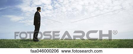 Businessman standing in grassy filed with hands in pockets, looking at view View Large Photo Image Stock Photograph - Businessman standing in grassy filed with hands in pockets, looking at view. Fotosearch