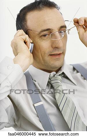 Businessman using cell phone, taking off glasses View Large Photo Image Stock Photography - Businessman using cell phone, taking off glasses. Fotosearch