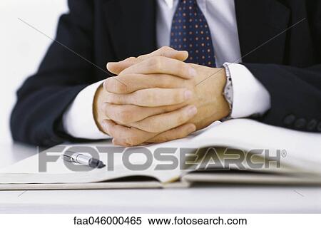 Businessman with hands clasped resting on open book, cropped View Large Photo Image Stock Photography - Businessman with hands clasped resting on open book, cropped. Fotosearch