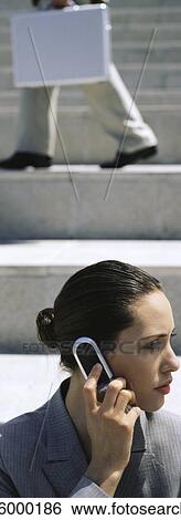 Stock Photograph - Businesswoman using cell phone, looking away. Fotosearch