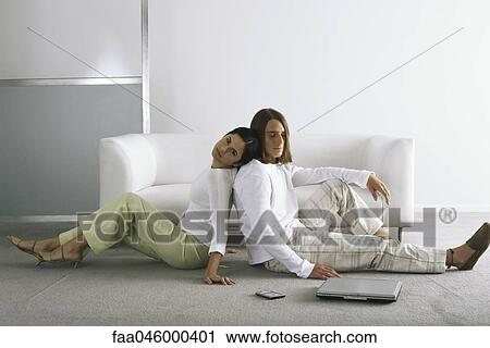 Stock Image - Couple sitting back to back on floor. Fotosearch