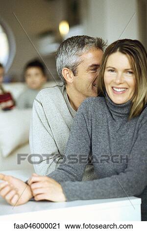 Couple sitting together, man whispering in woman's ear View Large Photo Image Stock Image - Couple sitting together, man whispering in woman's ear. Fotosearch
