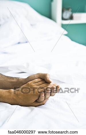Couple's clasped hands on bed View Large Photo Image Stock Photo - Couple's clasped hands on bed. Fotosearch
