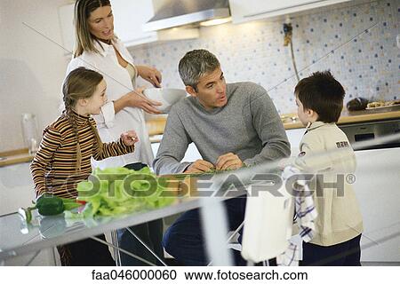 Family together in kitchen all listening to little boy View Large Photo Image Stock Image - Family together in kitchen all listening to little boy. Fotosearch